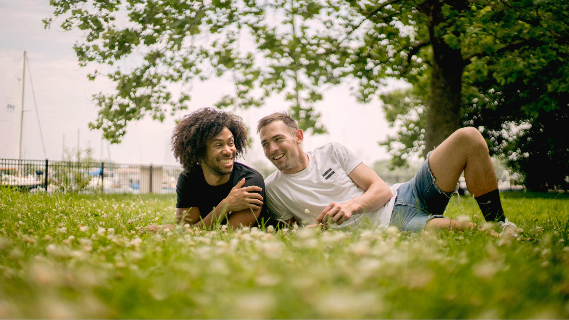 gay couple laying in the grass together both smiling on a sunny day, Katheryn Barton Uplift and Connect Counseling